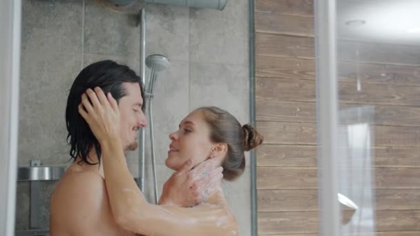 Zeitlupe von glücklich mädchen und kerl küssen im dusche, mann wäscht womans körper — Stockvideo