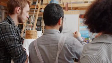 Profesyonel resim öğretmeninin arka planda iki öğrenciye resim çizdirmesi.