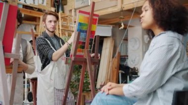 Erkek ve kadın sanat sınıfında genç Afro-Amerikalı kız modellerin portrelerini çiziyor.