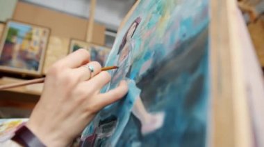 Resim stüdyosundaki kızın boya fırçasıyla yakın plan portresi.