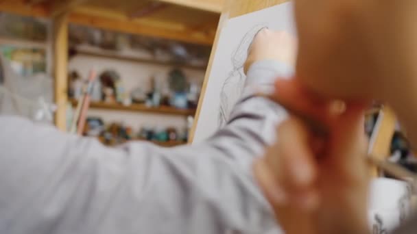 Primer plano del dibujo a mano masculino con lápiz que trabaja en clase de arte en interiores — Vídeo de stock