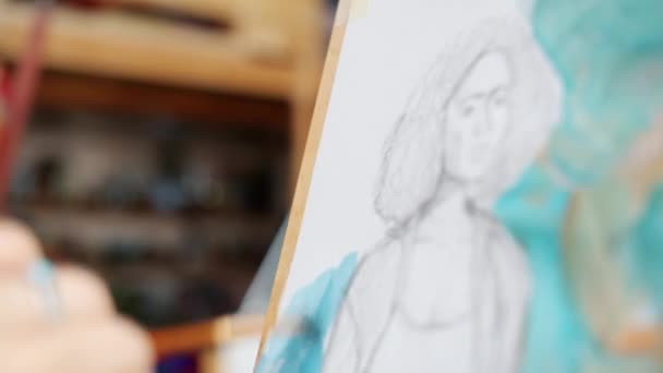 Close-up of girls hand painting portrait of woman with watercolors in studio — Stock Video