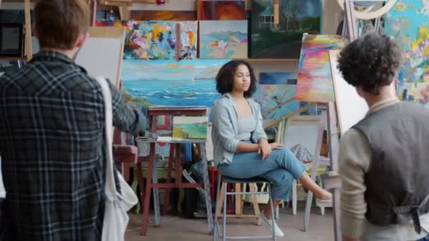 Afrikansk-amerikansk pige model udgør for gruppe af kunststuderende i moderne studie – Stock-video
