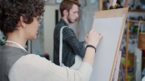 Homem e mulher estudantes de arte desenho fotos durante a aula de pintura em estúdio — Vídeo de Stock