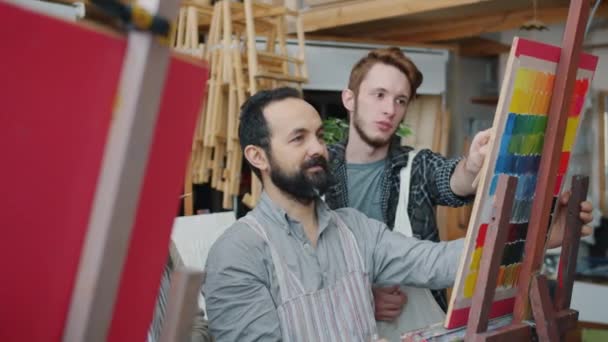 Artista experiente barbudo homem falando com grupo de estudantes de arte ensinando desenho em estúdio — Vídeo de Stock