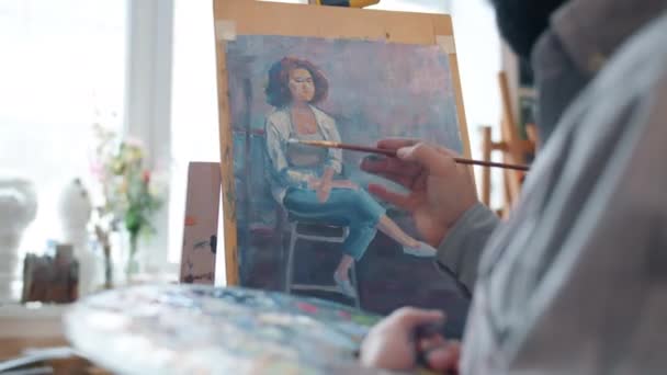 Talentoso artista masculino creando retrato de mujer joven trabajando en interiores en taller — Vídeos de Stock