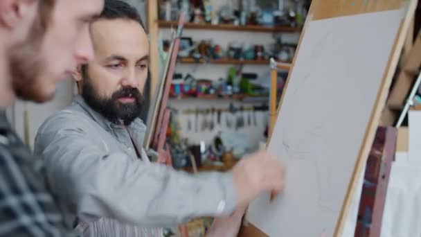 Professionell konstnär lära ung man amatör i målning klass rita porträtt tillsammans — Stockvideo