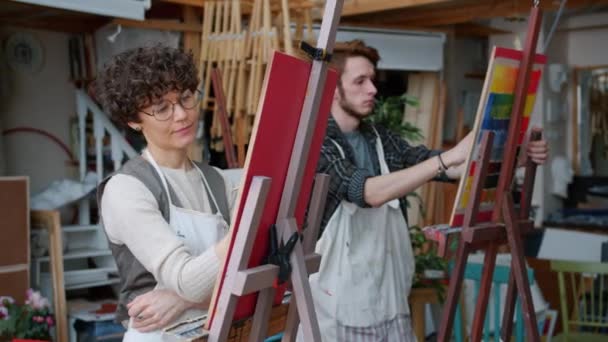 Κορίτσι και άντρας επιμελείς φοιτητές τέχνης που ζωγραφίζουν εικόνες στην τάξη απασχολημένος με τη δημιουργική εργασία — Αρχείο Βίντεο