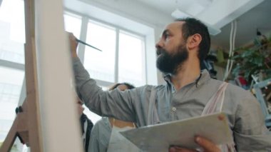 Çok ırklı öğrenciler izlerken yetenekli modern ressam soyut resim çiziyor.