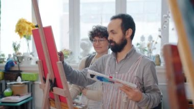 Profesyonel sanatçılarla sanat dersi sırasında resim çizen iki öğrenci.