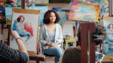 Kız ve erkek sanat öğrencileri, erkek öğretmenin rehberliği altında Afrikalı Amerikan modelinin portresini çiziyorlar.