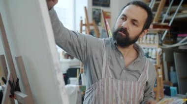 Çekici sakallı adam ressamı yavaş çekimde stüdyoda resim yapıyor.
