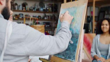 Deneyimli sanatçı, genç bayan öğrenciye, stüdyoda Afro-Amerikan modelinin portresi için yardım ediyor.