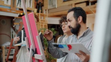 Paletli ve fırçalı bir adamın yavaş çekimde stüdyoda resim çizmesi.