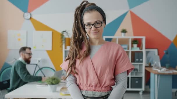 Slow motion portrait of beautiful young lady with dreadlocks smiling in creative office — Stock Video