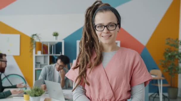 Rastalı ve piercingli neşeli genç bir kadının portresi ofiste gülümsüyor. — Stok video