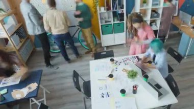 Tasarımcılardan oluşan yaratıcı ekibin uzaklaşması modern ofiste laptoplarla konuşarak çalışıyor.