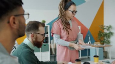 Yaratıcı tasarımcılarla konuşan ve ofiste renk örnekleri paylaşan genç bir kadın.