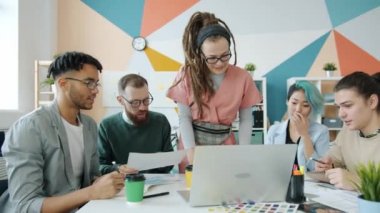Bir grup yaratıcı genç uzman ofiste dizüstü bilgisayara bakarak iş konuşuyorlar.