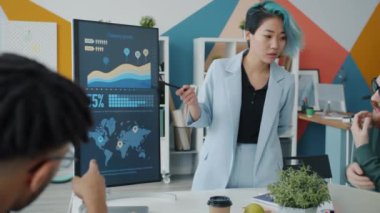 Ofisteki elektronik panoyu kullanarak iş dünyası için sunum yapan şık Asyalı kadın.