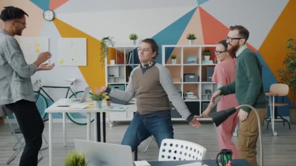 Movimiento lento de jóvenes excitados colegas bailando en el lugar de trabajo divirtiéndose riendo — Vídeos de Stock