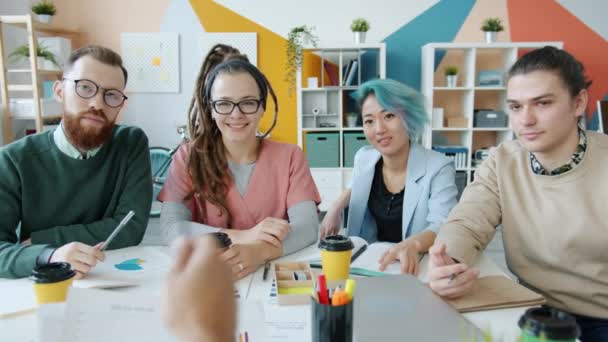 Portræt af multietnisk gruppe af unge, der kigger på kamera og taler under et møde i kontoret – Stock-video