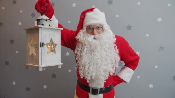 Портрет людини в костюмі Санта, що тримає ліхтар і посміхається дивитися на камеру — стокове відео