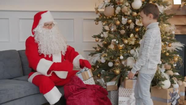 Babbo Natale che dà la scatola regalo al bambino che si congratula con il bambino per Natale a casa — Video Stock