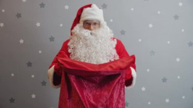 Noel Baba 'nın portresi yılbaşı günü kameraya hediye dolu bir çantayla kollarını açıyor.