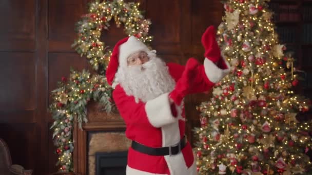Langzame beweging van de mens in de kerstman kostuum dansen binnen in versierde kamer plezier hebben — Stockvideo