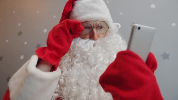 Cara séria em roupa de Papai Noel usando tela de toque de smartphone no fundo estrelado — Vídeo de Stock