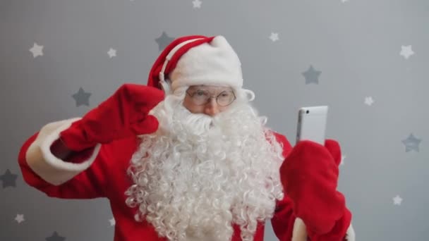 Weihnachtsmann mit Kopfhörer schaut auf Smartphone-Bildschirm und tanzt Spaß — Stockvideo