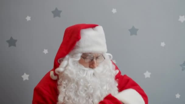 Weihnachtsmann hebt Tüte mit Geschenken in die Kamera und zwinkert auf Sternenhintergrund — Stockvideo