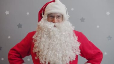 Noel Baba 'nın portresi kafa fonları takıyor ve gri yıldızlı arka planda müzik dinliyor.