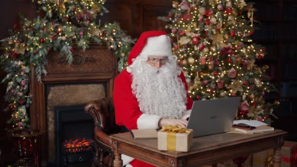 Άγιος Βασίλης χρησιμοποιώντας πληκτρολόγηση laptop επικεντρώθηκε στην εργασία σε διακοσμημένο σπίτι την Πρωτοχρονιά — Αρχείο Βίντεο