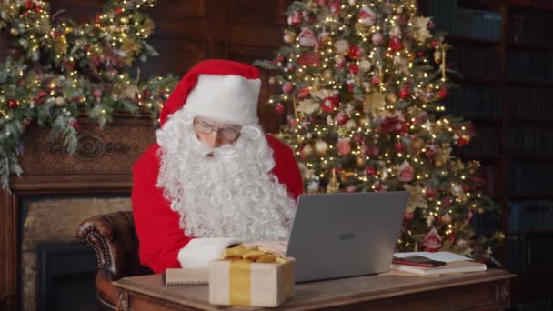 Papá Noel trabajando con ordenador portátil en estudio decorado en Nochebuena — Vídeos de Stock