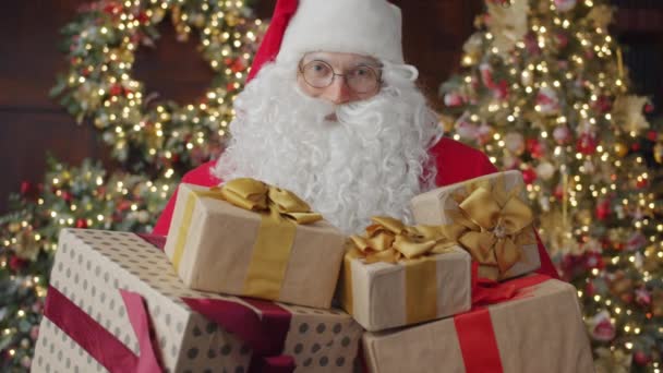 Retrato del hombre en traje de Papá Noel sosteniendo cajas de regalo de Año Nuevo en el interior — Vídeo de stock