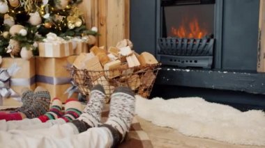 Ayakların yakın çekimi büyük ve küçük hareketler yeni yıl tarzı çoraplar, arka planda yanan şömine.