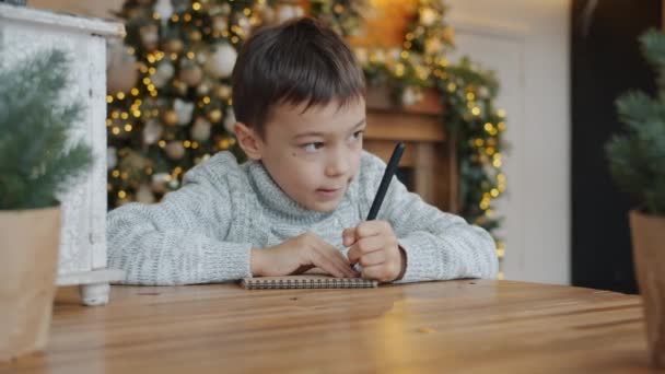 Movimento lento de criança adorável escrevendo carta para Papai Noel no apartamento — Vídeo de Stock