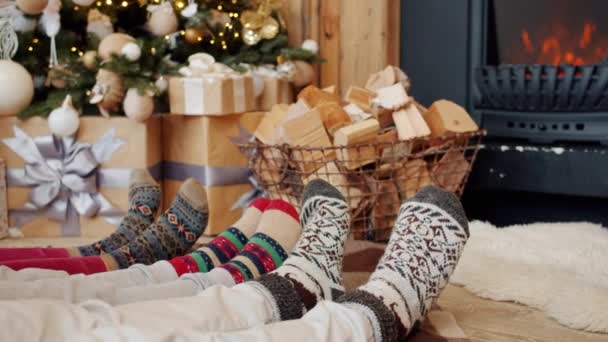 Gros plan ralenti des pieds se détendre sur le sol la veille de Noël, cheminée et arbre décoré sont visibles — Video