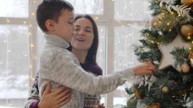 Anne ve küçük oğlu Noel ağacına top asıp evde konuşuyorlar.