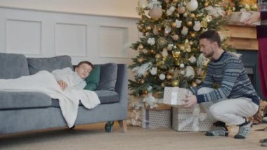 Anne ve babanın çocuk uyurken yeni yıl ağacının altına hediye kutuları koyması.