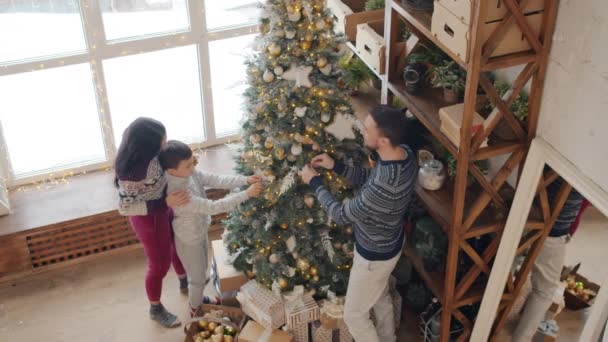 Vista de ángulo alto de la madre, el padre y el hijo decorando el árbol de Navidad en casa — Vídeos de Stock