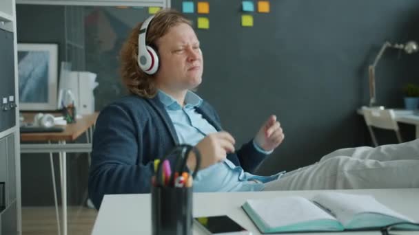 Повільний рух щасливого бізнесмена, який слухає музику, насолоджуючись піснею в офісі — стокове відео