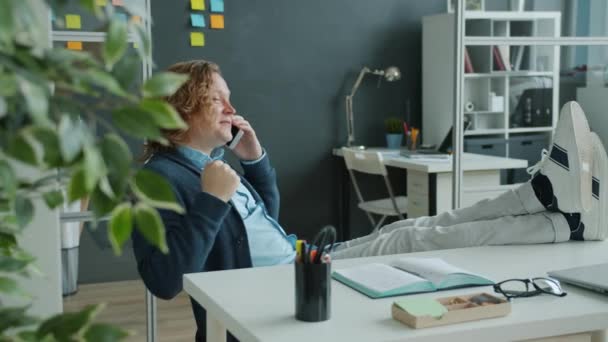 Feliz hombre de negocios hablando por teléfono móvil y haciendo gestos disfrutando de la comunicación empresarial en la oficina — Vídeos de Stock