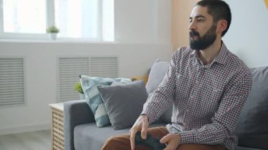 İyi görünümlü melez adamın dairede video oyunu oynaması ağır çekim.