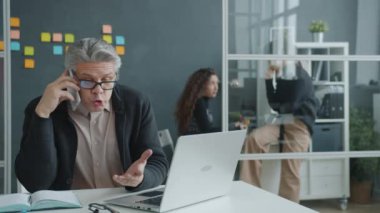 Deli ofis çalışanı cep telefonuyla bağırarak iş anlaşmazlığını tartışıyor sonra da masaya vuruyor.