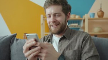Modern dairede akıllı telefon mesajları kullanan yakışıklı adam yavaş çekim yapıyor.