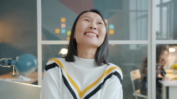 Retrato de mujer asiática feliz sonriendo y riendo sentado en el escritorio en la oficina — Vídeos de Stock