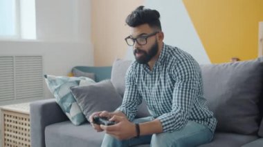 Yavaş çekimde melez adam evdeki kanepede video oyunundan zevk alıyor.